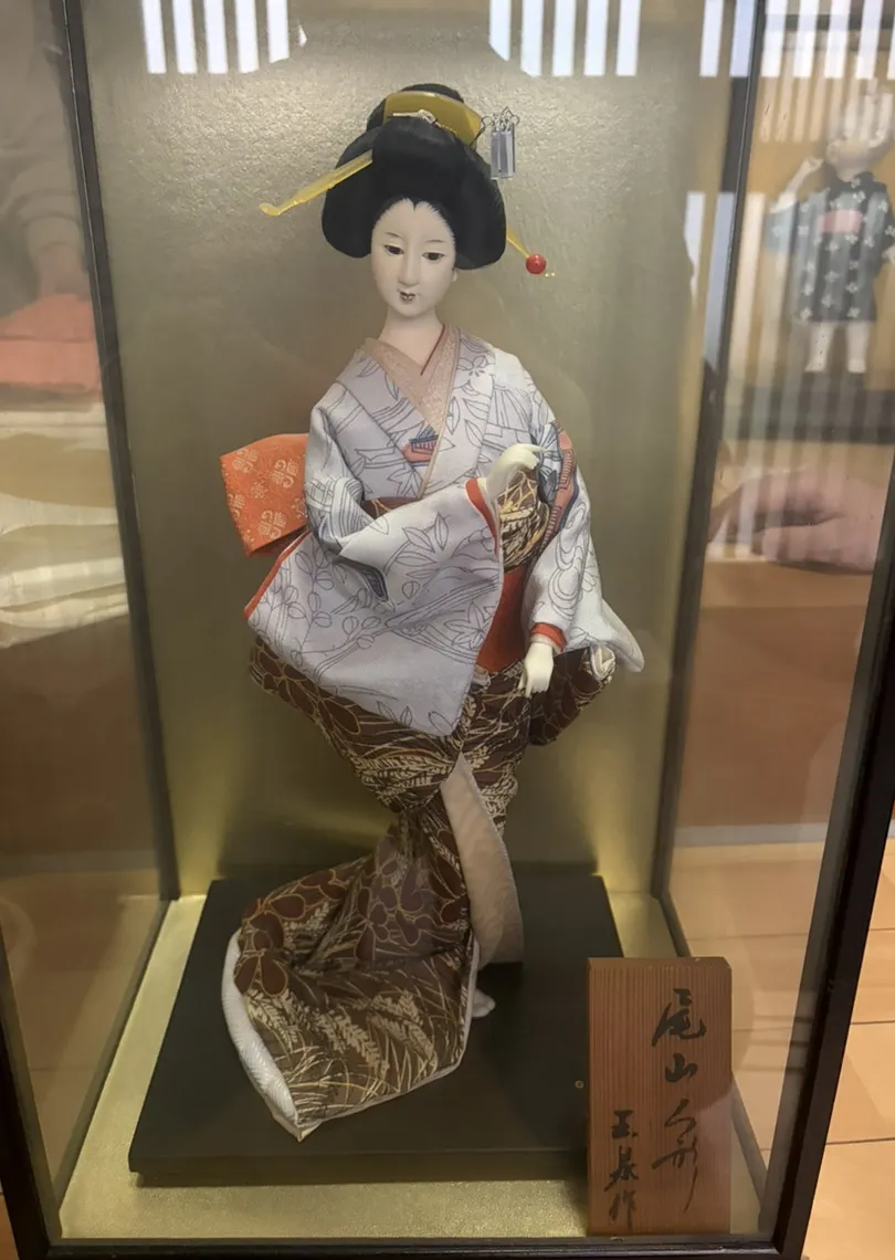 ガラスケース入りの日本人形。作者の銘が入った木札付き
